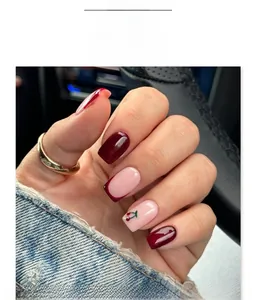 Close-up of wine red and pink press-on nails with cherry art and french tips