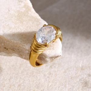Macro detail of 18k gold plated ring featuring an oval white gemstone on natural stone