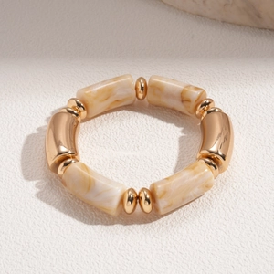 Detail of beaded stretch bracelet with golden metal tubes and cream marble resin