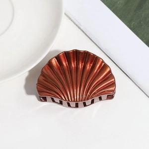 Detailed view of dark brown shell-shaped hair claw with glitter finish on white background