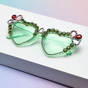 Close-up of heart-shaped sunglasses with green rhinestones and colorful crystal accents