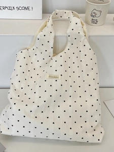 Minimalist white textured canvas tote bag with black heart patterns and woven label