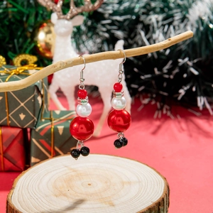 Boucles d'oreilles de Noël festives avec perles rouges et blanches sur une branche