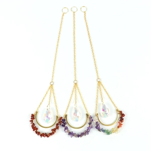 Detailed view of three gold U-shaped suncatchers with natural stones and crystal prisms