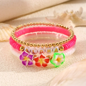 Dettaglio dei braccialetti da spiaggia con scritte ALOHA, fiori e stella marina
