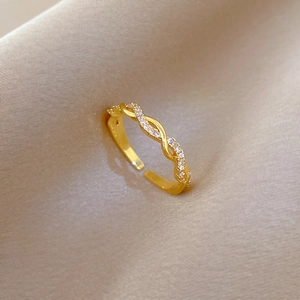 Nahaufnahme des goldenen Zirkonia-Rings mit Seilstruktur auf Champagner-Satin