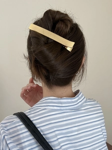 Gros plan sur la barrette dorée rectangulaire en métal portée sur un chignon chic