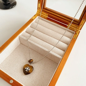 Detail of a vintage heart pendant with cross motif in a premium wooden jewelry box