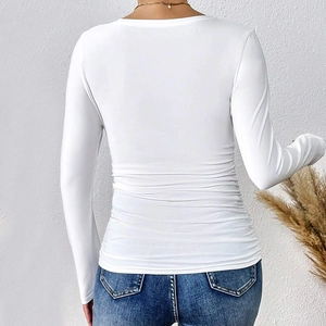 Detalle del diseño fruncido lateral y del tejido de punto elástico de la camiseta blanca de manga larga