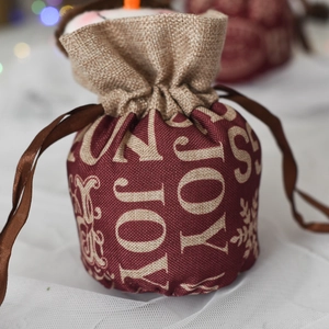 Close-up of Christmas drawstring gift bag with red JOY print and linen stitching details