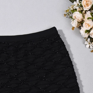 Détail de la jupe courte noire avec texture ondulée 3D et fils métalliques brillants
