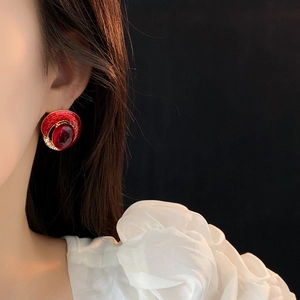 Close-up of vintage gold and red enamel earrings with gemstone inlay worn by a model