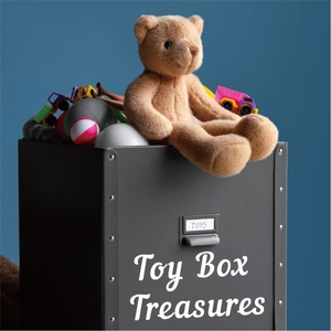 Detail of a black industrial toy box with metal rivets and plush teddy bear inside