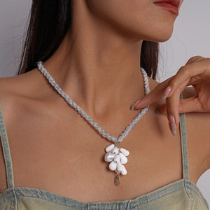 Detail of silver woven chain necklace with white baroque bead cluster on a model