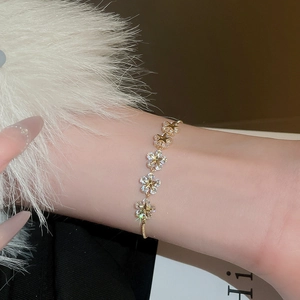 Detailed close-up of a gold-plated flower bracelet with zircon star elements on wrist