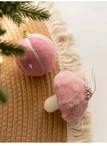 Close-up of pink plush Christmas ornaments with gold glitter and beads on a festive background