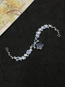 Macro detail of hand-woven bracelet with light blue floral charms and pearl accents