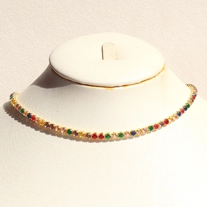 Detailed close-up of rainbow tennis necklace with colorful round-cut stones on gold chain