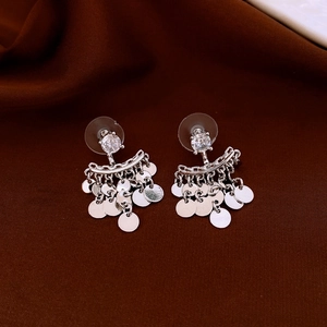 Detail view of silver tassel earrings with zircon studs on dark velvet background