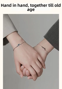 Detail of couple bracelets with mountain and ocean enamel charms on wrists