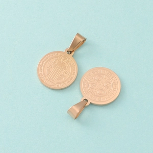 Macro shot of rose gold Saint Benedict medal charms with intricate religious engraving