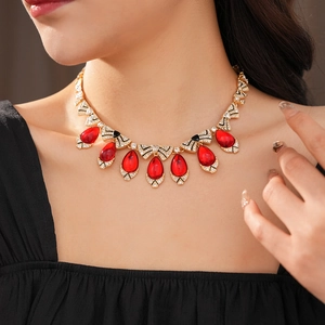 Model wearing vintage gold necklace with red teardrop stones and rhinestone bow accents