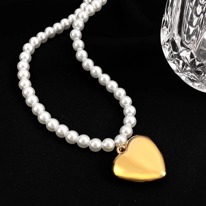 Vintage pearl body chain featuring a large polished 3D gold heart pendant on black fabric