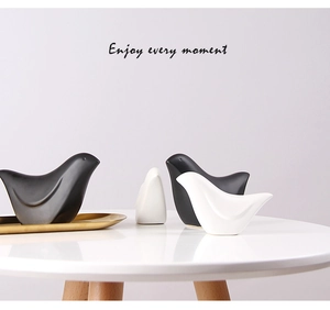 Minimalistische Keramikvögel in Schwarz-Weiß auf einem goldenen Metalltablett