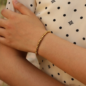 Women's gold beaded bracelet with faceted metallic hematite beads on wrist