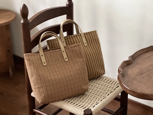 Close-up of vintage plaid canvas tote bags with reinforced handles on a retro chair