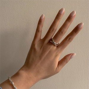Detailed view of elegant 925 sterling silver knotted ring and bracelet on model's hand