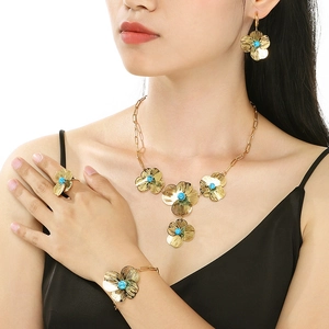 Golden flower jewelry set with turquoise stones featuring necklace, earrings and ring on model