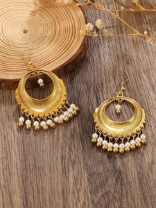 Close-up of bohemian hollow crescent earrings with white seed beads on wood surface