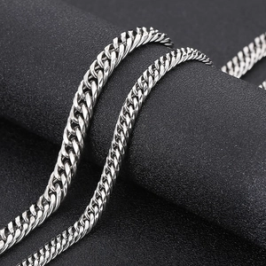 Gros plan d'un collier chaîne gourmette en acier argenté sur fond texturé noir