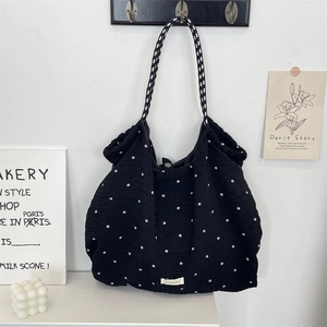 Détail d'un sac cabas noir matelassé à fleurs suspendu contre un mur minimaliste