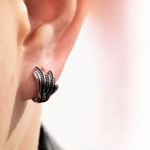 Close-up detail of retro stainless steel feather wing hoop earring in gothic style