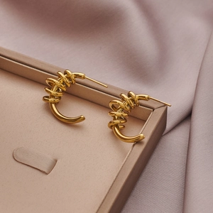 Detailed view of gold spiral earrings with hammered texture on a soft satin background
