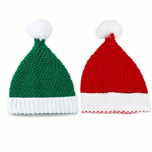 Close-up of red and green knitted Christmas hats showing coarse crochet texture and pompoms