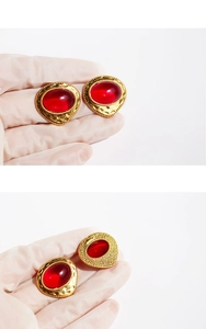 Macro view of vintage gold clip-on earrings with large red oval stones and metal back detail