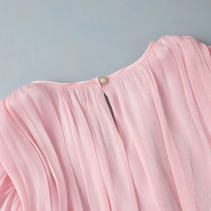 Detail of pink pleated dress neckline with pearl button closure and back teardrop opening