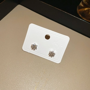 Detail of silver snowflake stud earrings with sparkling zircons on a white display card