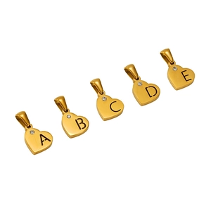Gold heart-shaped alphabet pendants with rhinestones letters A to E on white surface