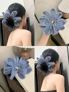 Detail of blue and white checkered fabric hair scrunchie with lace edge and black pom-pom