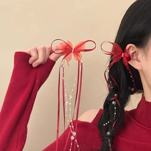 Detail of red bow hair clip with elegant streaming ribbons and delicate pearl beads