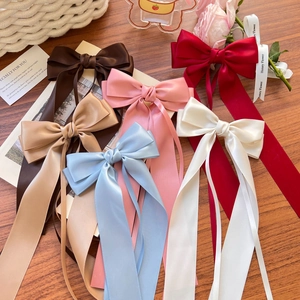 Elegant satin ribbon bow hair clips in multiple colors displayed on a rustic wooden desk