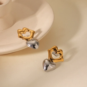 Close-up of two-tone gold and silver heart-shaped earrings with a metallic finish