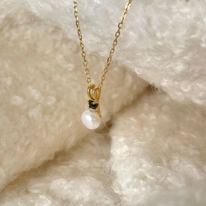 Elegant 925 silver necklace featuring a white pearl and black diamond on a gold chain
