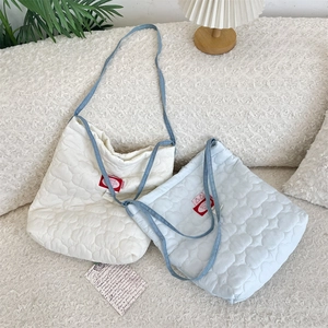 Détails de surpiqûres matelassées en cœur et anses en denim bleu sur sac fourre-tout