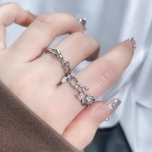 Close-up of irregular silver twig rings with clear gemstone on a white fabric background