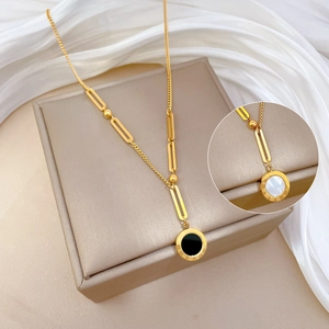 Detail of Roman numeral pendant with black and white shell inlay on a gold chain